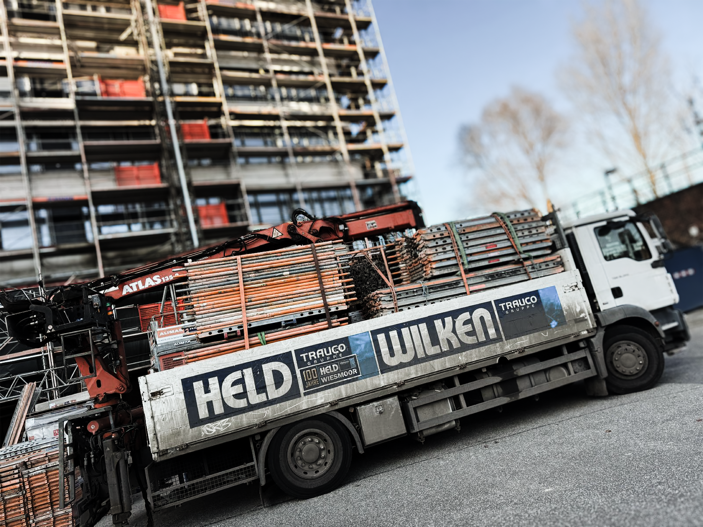 Transporter mit Gerüsten vor Baustelle